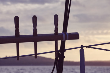 Vintage toned picture of an old sailing ship rigging elements silhouettes at sunset, selective focus.