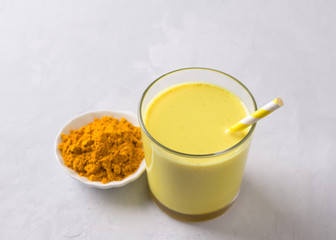 Golden milk with turmeric in a glass on a gray stone background. healthy natural energy drink. selective focus