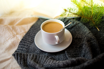 cup of tea with milk on a textile background with a knitted sweater and  needles.