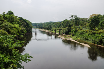 Obraz premium Crumbling iron and concrete bridge crossing Munaya river in rain forest of Cameroon, Africa.