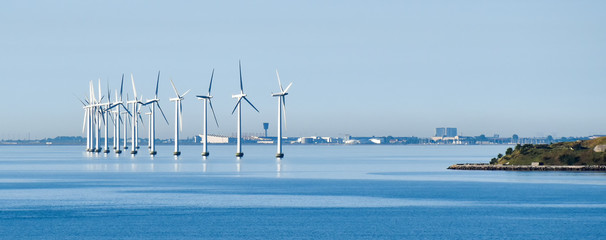 Offshore wind turbines on the coast of Copenhagen in Denmark with the airport in the background