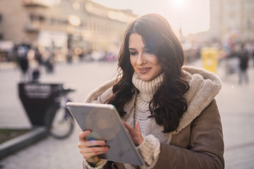 Young woman standing on the street and using tablet. Women using technology outdoors concept.