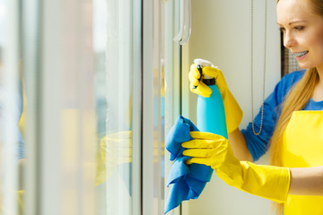 Girl cleaning window at home using detergent rag