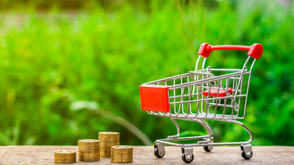 Empty shopping cart and a golden coins on the table. - Business and e-commerce concept.