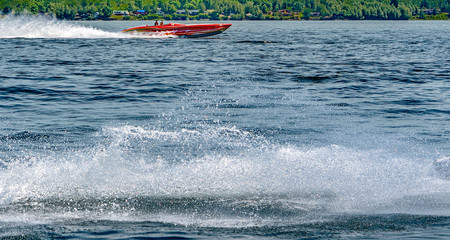 Red speedboat with a splash tail in the foreground