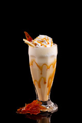 Closeup glass of caramel milk shake isolated at black background.
