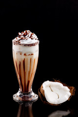 Glass of chocolate and coconut milk shake decorated with whipped cream isolated at white background.