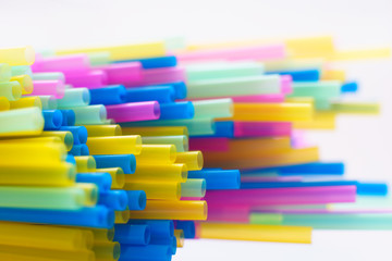 Multiple plastic straws laying on a white background