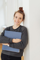 Attractive young student clutching a large binder