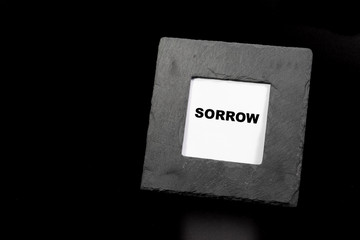 Picture frame with sorrow lettering inside isolated on black background