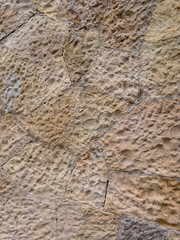 Brown wall of stone blocks of irregular shape and uneven surface for use as a background close up