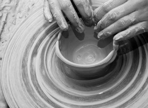 Hands of woman in process of making clay bowl on pottery wheel