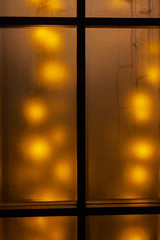 The golden Christmas garland shine through the frosted glass door. Fine concept of New year background