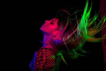 Alternative model with bangs and colored hair poses under pink, blue, and green light wearing a fishnet top - 230682960