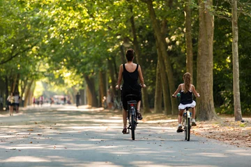Fototapeten A woman and a girl biking in a sunny Amsterdam Vondelpark in the Netherlands. © misign