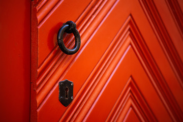 Antique metallic door knob on a red wooden door