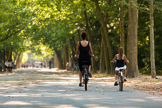 A woman and a girl biking in a sunny Amsterdam Vondelpark in the Netherlands.