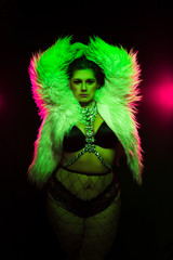 Curvy alternative model with colored hair and fur coat and fishnets under green and pink lighting