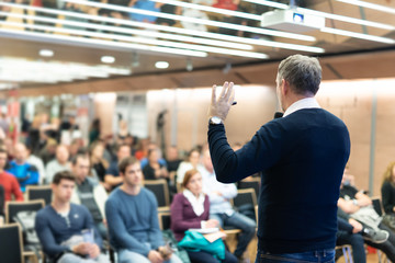 Expert giving a talk on business conference workshop. Unrecognizable people in audience at the...