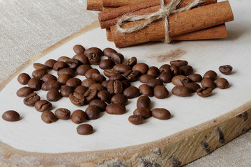 Roasted coffee beans and cinnamon sticks on a wooden stand and coarse jute canvas.