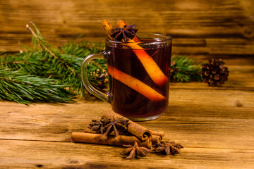 Cup of mulled wine with cinnamon and fir tree branches on wooden table