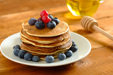 Stack of pancakes with fresh blueberries and maple syrup