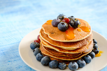 Stack of pancakes with fresh blueberries and maple syrup