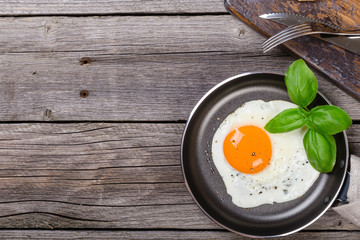 Fried egg with basil on pan