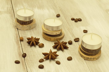 Obraz na płótnie Canvas Elements of Christmas interior decor. Sleeve candles on wooden coasters roasted coffee beans and star anise on light wooden background.