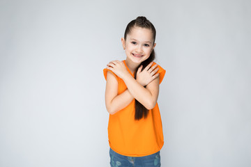 Naklejka premium Girl on a gray background folded his hands at his chest.