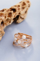 Stylish gold ring with pearls and diamonds on blue background
