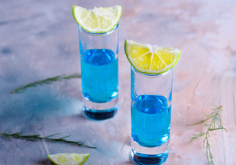 Delicious blue drink with a handful of green lemon. Cocktail with limnom concrete background. Blue cocktail with lemon.
