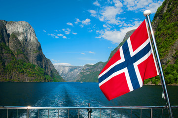 The Breathtaking Norwegian Aurlandsfjord and Naeroyfjord - UNESCO protected fjord - cruise (Flam- Gudvangen) on Norway in a Nutshell Tour. One of the narrowest fjords in Europe Naeroyfjord and a flag. © Liaurinko