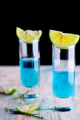 Delicious blue drink with a handful of green lemon. Cocktail with limnom concrete background. Blue cocktail with lemon.