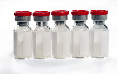 Glass medical vials of biotech drugs with red caps. Isolated on white background.