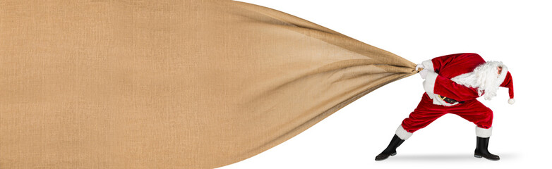 Santa claus in hopeless fight to pull huge big natural jute gift bag with copy space texture isolated on white background