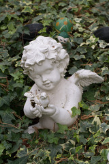kleine engelsfigur mit taube in der hand auf einem grab