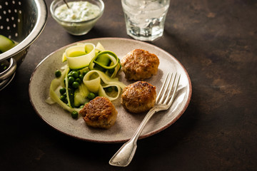 Chicken meat balls with zucchini salad and green peas, with garlic-yogurt sauce.