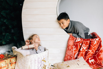 Little girl and boy sitting on the background of the moon and the baskets decorated under the new Year