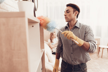 Arab Male Removes Dust from Shelf in Apartment.