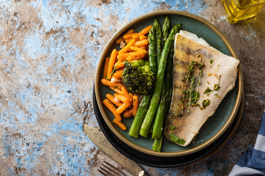 Pike perch fillet with asparagus, broccoli and carrots. Fried fish with stewed greens