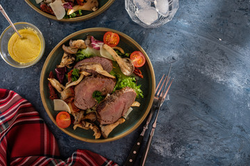 Salad with warm beef with oyster mushrooms, tomatoes and greens. Top view