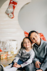 Little girl and boy sitting on the background of the moon and the baskets decorated under the new Year