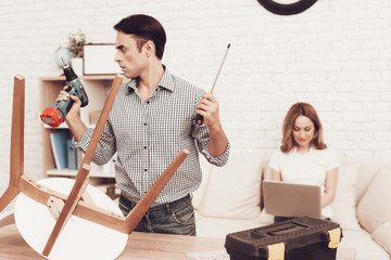 Furniture Assembler Looking Drill in Hand and Girl