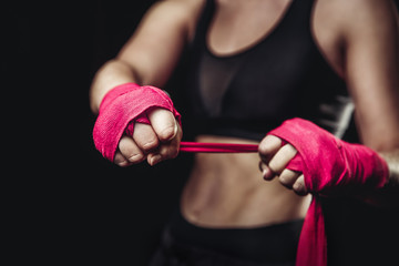Woman wraps her fists in pink bandages for boxing gloves