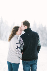 Fototapeta premium happy loving couple walking in snowy winter forest, spending christmas vacation together. Outdoor seasonal activities. Lifestyle capture.