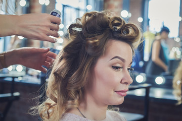 Fototapeta premium Young european woman is getting hair style service in a beauty shop.