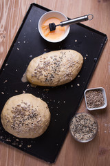 The dough sprinkled with seeds in the form of baking bread