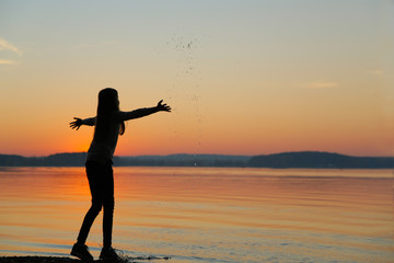 A teenager at sunset makes the water spray