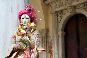 Fototapeta na wymiar Carnival pink-gold-beige mask and costume at the traditional festival in Venice, Italy